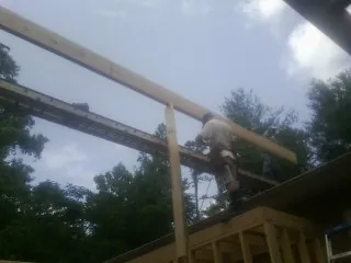 Carpenter setting a ridge beam over a new addition frame — Ice Dam Removal by Roofing Brothers in Thrall