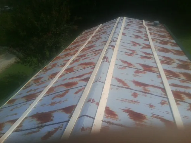 Rusted metal roof panels with new wood purlins before replacement — Storm Damage Roof Repair in Thrall by Roofing Brothers
