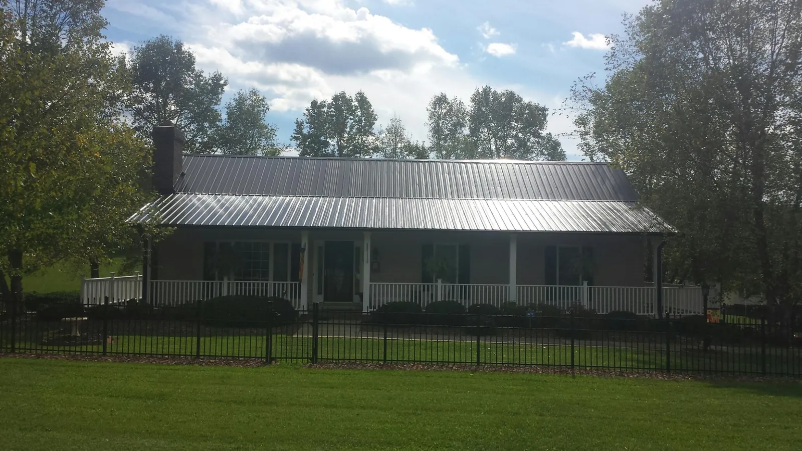 Gray metal roof on a brick ranch with a full width front porch — Gutter Guard Installation work by our crew in Thrall