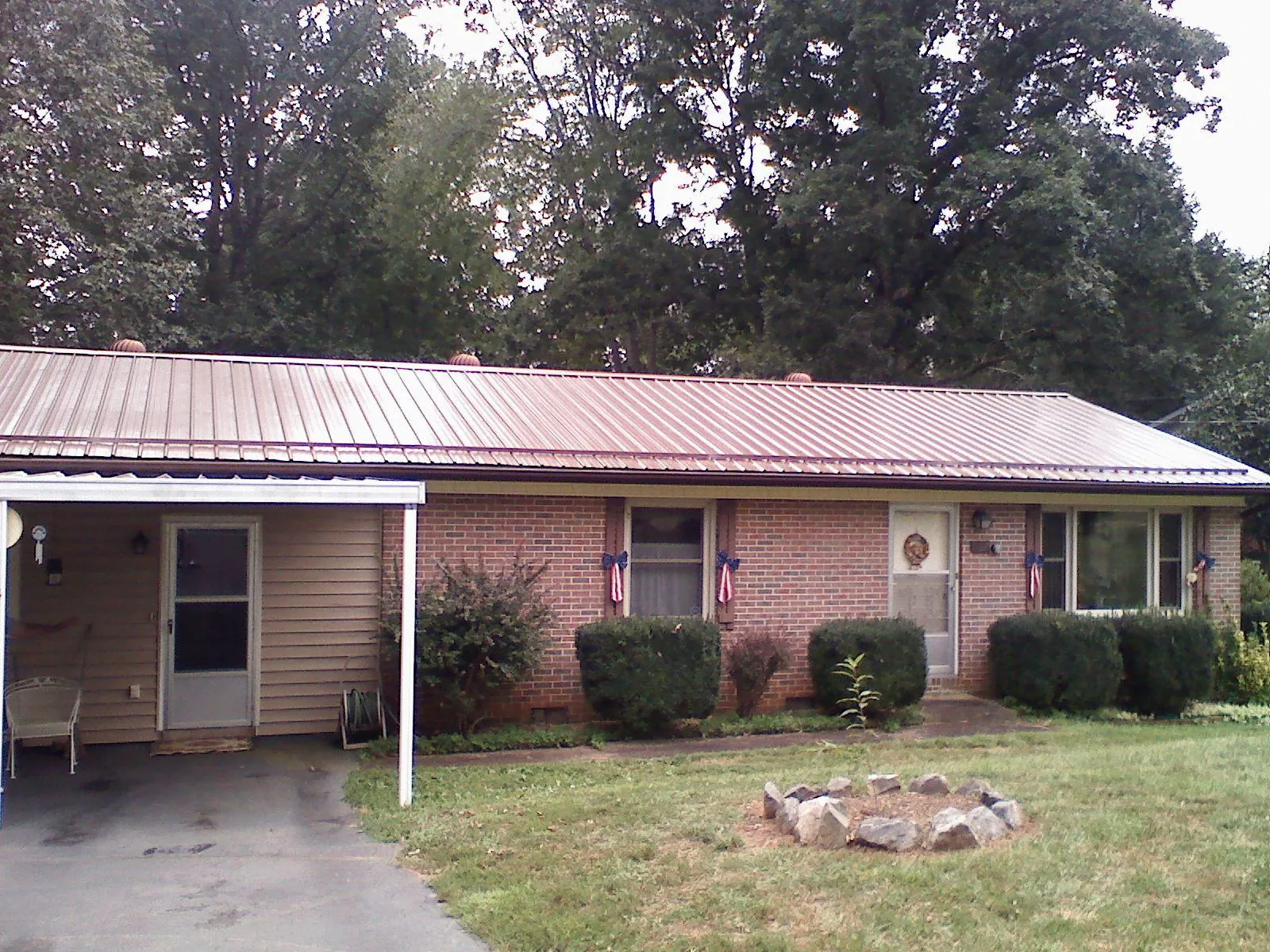 Bronze metal roof and carport on a brick ranch home — Roof Repair work by our crew in Thrall
